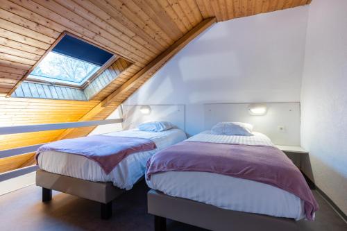 two beds in a attic bedroom with a window at Hotel-Restaurant Espace Squash 3000 in Mulhouse