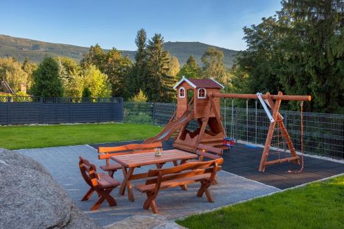 a playground with a wooden bench and a slide at ARAMIKA apartamenty in Szklarska Poręba