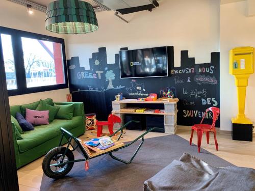 a living room with a green couch and a tv at greet Hotel Beaune in Beaune