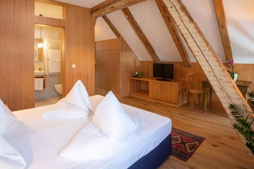 a bedroom with a white bed and a television at Hotel Baur Am See in Dobbiaco
