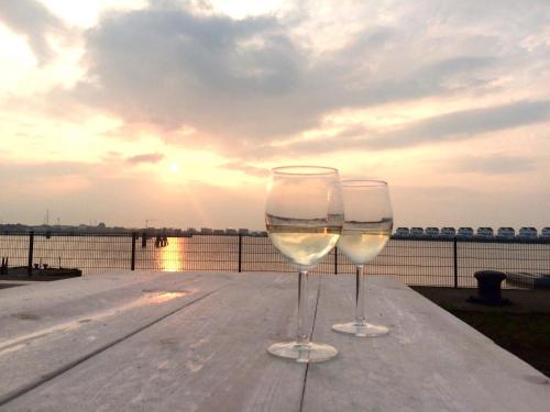 dos copas de vino sentadas en una mesa cerca del agua en Marina Lodge en Olpenitz