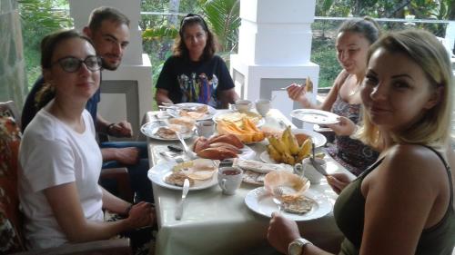 un grupo de personas sentadas alrededor de una mesa comiendo comida en House of Richness, en Negombo