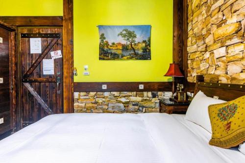 a bedroom with a bed and a stone wall at Provence Rose Lodge in Renai