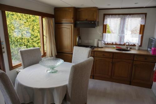 a kitchen with a white table and chairs and a kitchen with a window at Chalet at a holiday park in Opmeer near Amsterdam in Opmeer