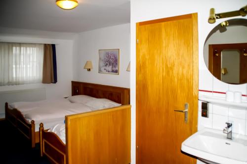 Hotel Sonne في لورخ: غرفة نوم بسرير ومغسلة ومرآة
