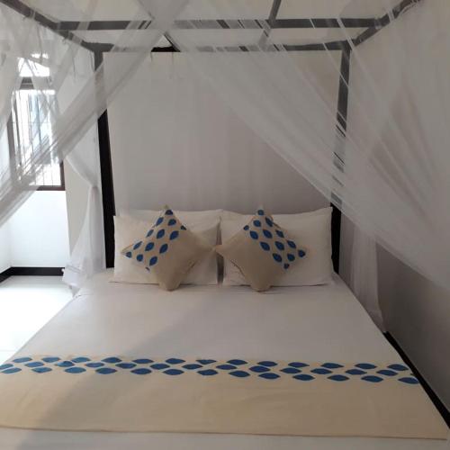 a white bed with four pillows in a room at Apna Homestay Apartments in Unawatuna