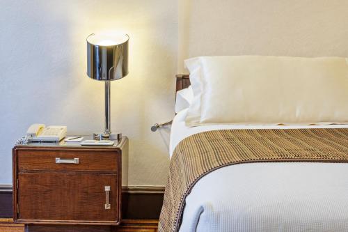 a bed with a lamp and a phone on a night stand at Hotel Britania Art Deco - Lisbon Heritage Collection - Avenida in Lisbon