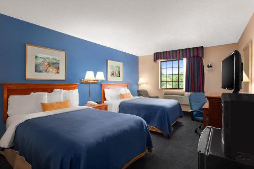 a hotel room with two beds and a flat screen tv at Days Inn by Wyndham Keene NH in Keene