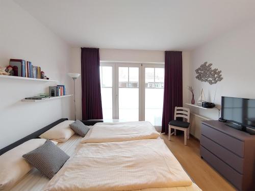 a bedroom with two beds and a tv and a desk at Auszeit am Meer in Wittdün