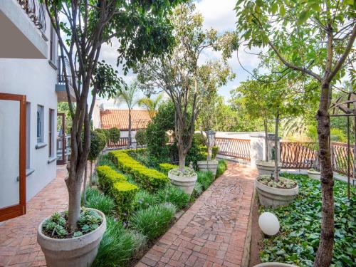 un jardin avec des arbres et des plantes et une passerelle en briques dans l'établissement Bohemian House - Pretoria, à Pretoria
