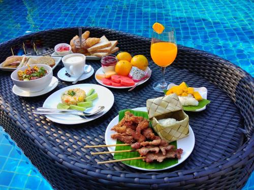 een tafel met borden en een glas sinaasappelsap bij Nimman Villa 17 Chiangmai - SHA PLUS in Chiang Mai