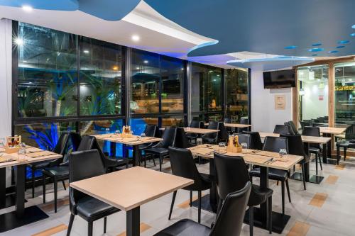 a restaurant with tables and chairs and windows at LawinTa Hotel Pattaya in Jomtien Beach