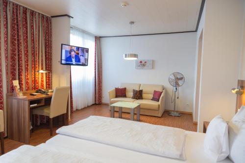 Habitación de hotel con cama, escritorio y TV. en Das Ebertor - Hotel & Hostel en Boppard