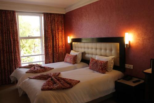 2 letti in una camera d'albergo con pareti rosse di Hotel Al Walid a Casablanca