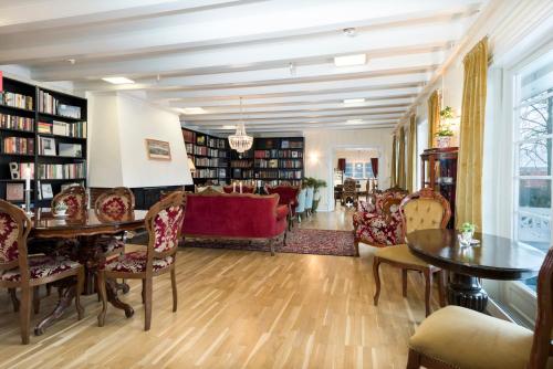 a library with a red couch and tables and chairs at Pilegrimsgården Hotell og Gjestegård in Trondheim