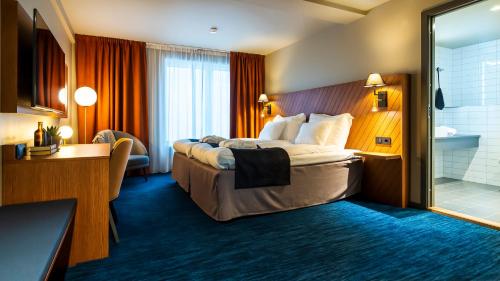 a hotel room with a large bed and a bathroom at Home Hotel Fregatten in Varberg