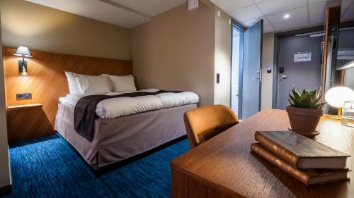 a bedroom with a bed and a desk with a table at Home Hotel Fregatten in Varberg