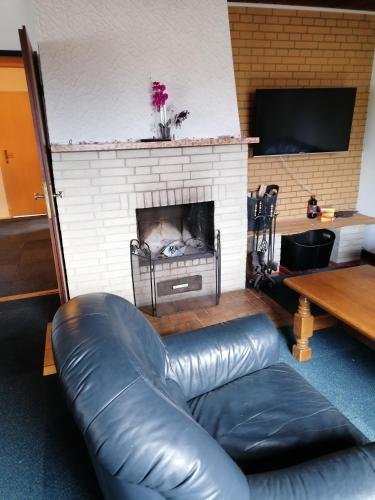 un sofá de cuero en una sala de estar con chimenea en Haus Rotenburg, en Rotenburg an der Fulda