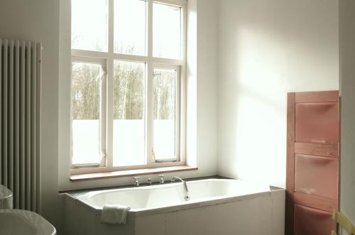 a bathroom with a bath tub and a window at Zöllnerhaus Nordhorn in Nordhorn