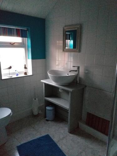 a bathroom with a sink and a toilet and a window at Bank End in Egremont