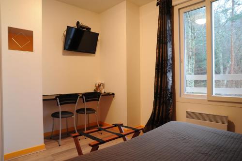 - une chambre avec un bureau, un lit et une fenêtre dans l'établissement Hôtel du Lac, à Treignac