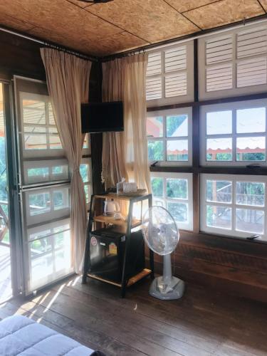 a room with windows and a fan and a desk at Phayam Valley Homestay in Ko Phayam