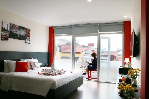 a bedroom with a bed and a woman sitting in a chair at AncyrA TamTam Hotel by Continent - Near Hoan Kiem Lake in Hanoi