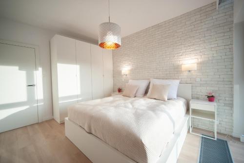 ein weißes Schlafzimmer mit einem Bett und einer Ziegelwand in der Unterkunft FEWO Sea View Porta Mare in Dziwnówek