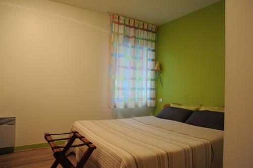 a bedroom with a bed and a green wall at Hôtel du Lac in Treignac