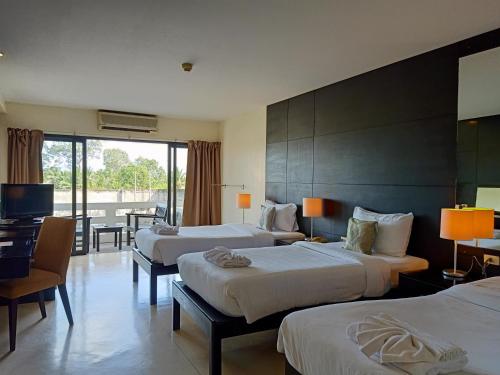 a hotel room with two beds and a television at Amarin Samui Hotel - SHA Plus Certified in Mae Nam