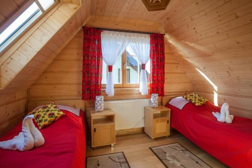 two beds in a log cabin with a window at Całoroczne Domki Góralskie Kluszkowce-Czorsztyn in Kluszkowce