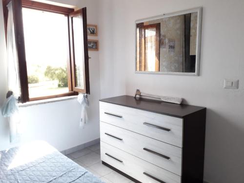 a bedroom with a dresser with a mirror and a window at Bilocale Li Menduli in San Teodoro