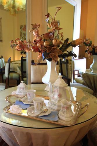 a table with cups and saucers and a vase with flowers at B&B Pretoria Suite in Potenza