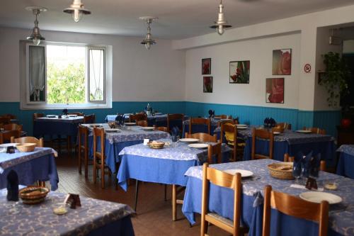 un comedor con mesas y sillas azules y una ventana en Hotel Ornella, en Lido di Camaiore
