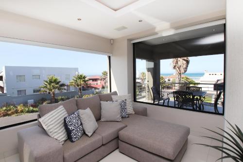 a living room with a couch and a large window at C' la Vie Luxury Accommodation in Melkbosstrand