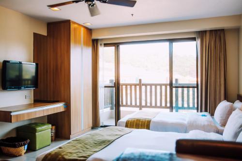 um quarto de hotel com duas camas e uma varanda em Azalea Residences Baguio em Baguio