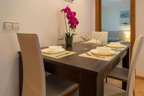 einen Esstisch mit weißen Stühlen und einen Holztisch mit lila Blumen in der Unterkunft Moderno apartamento en Valencia para 6 personas in Valencia