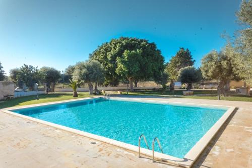 a swimming pool in a park with trees in the background at Masseria Testaferrata in Siracusa