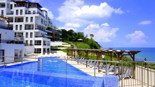 a swimming pool in front of a building next to the ocean at Апартаменти Бяла Клиф - Byala Cliff Apartments in Byala