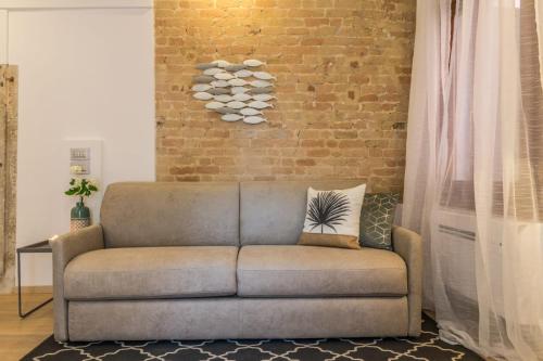a couch in a living room with a brick wall at Home Venice Apartments - Biennale 1 - 2 - 3 in Venice