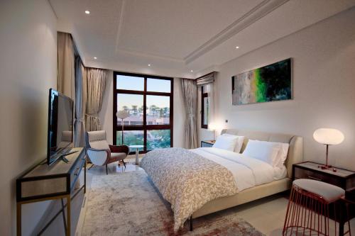 a bedroom with a bed and a television and a window at Dibba, Villa 61 - Mina Al Fajer, Dibba Al Fujairah in Rūl Ḑadnā
