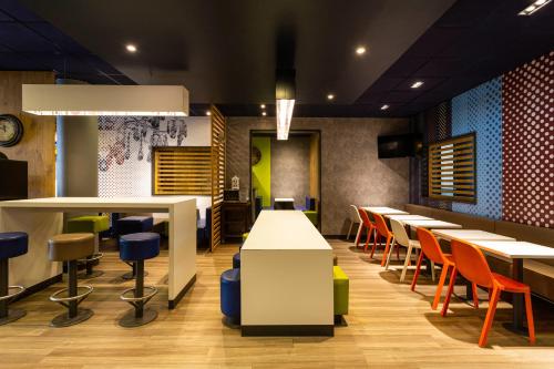 a restaurant with tables and chairs and a clock at ibis budget Bordeaux Centre - Gare Saint Jean in Bordeaux