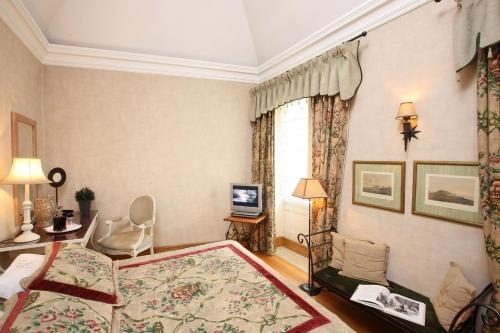 a hotel room with a bed, chair, table and lamps at Solar do Castelo - Lisbon Heritage Collection - Alfama in Lisbon