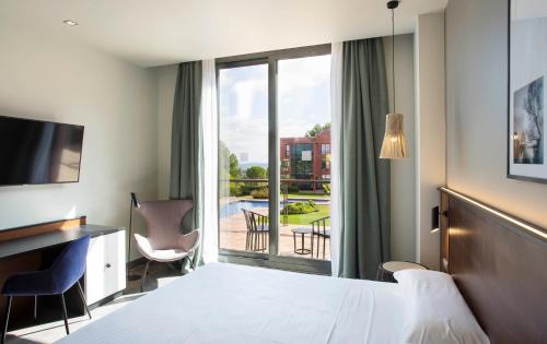 Habitación de hotel con cama, escritorio y ventana en Hotel Barcelona Golf Resort 4 Sup, en Martorell