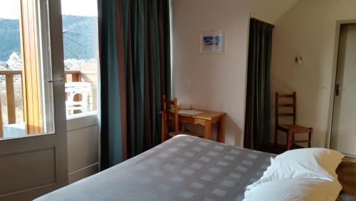 a bedroom with a bed and a large window at Hôtel Restaurant Les Tilleuls in Autrans
