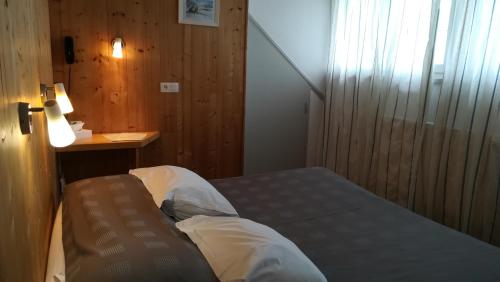 a small bedroom with a bed and a table at Hôtel Restaurant Les Tilleuls in Autrans