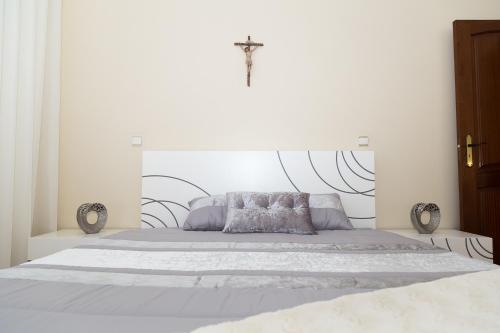 a white bedroom with a large bed with a cross on the wall at Mar Rosa in Aguçadoura