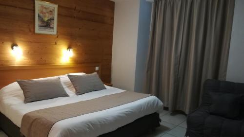 a hotel room with a bed and a chair at Hôtel Restaurant Les Tilleuls in Autrans