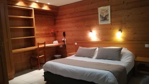 a bedroom with a bed and a wooden wall at Hôtel Restaurant Les Tilleuls in Autrans