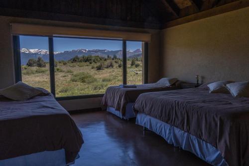 a room with two beds and a large window at Hostería La Chira in San Martín de los Andes